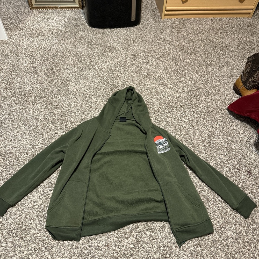 Green zip-up jacket for small kids, featuring a cozy hood and soft fabric